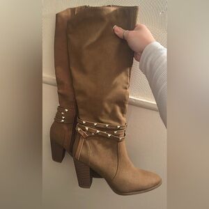 Jennifer Lopez brown knee-high boots with studded straps.